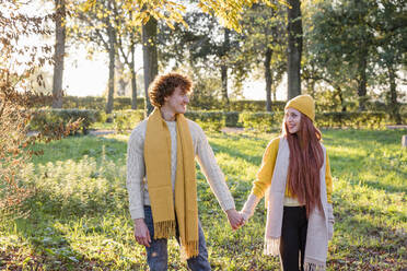 Smiling couple holding hands standing together at park - EIF03291