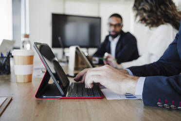 Geschäftsmann tippt auf Laptop am Schreibtisch im Büro - EBBF05269