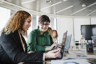 Geschäftsfrau, die mit einem Kollegen im Büro eine Strategie am Laptop bespricht - EBBF05291