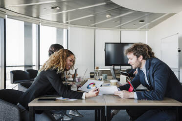 Businessman discussing strategy with young businesswoman in board room - EBBF05298