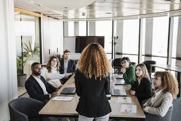 Geschäftsfrauen und Geschäftsmänner hören Kollegen zu, die im Sitzungssaal eine Strategie diskutieren - EBBF05309