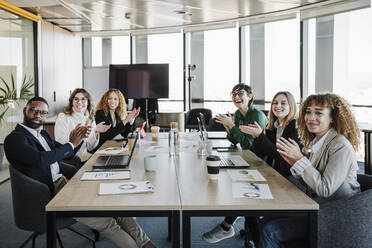 Glückliche Geschäftsfrauen und Geschäftsmann applaudieren bei einem Treffen - EBBF05311