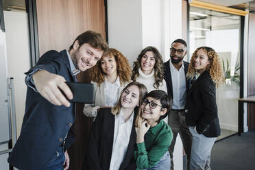 Glückliche Geschäftsleute und Geschäftsfrauen, die ein Selfie mit ihrem Mobiltelefon im Büro machen - EBBF05328