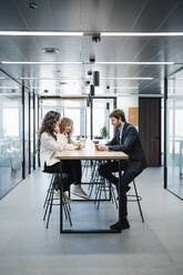 Businessman and businesswomen sitting at desk in office - EBBF05352