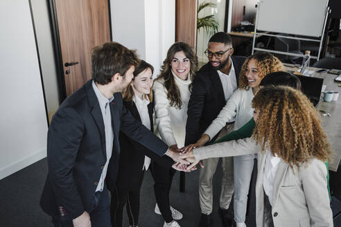 Glückliche Geschäftsleute und Geschäftsfrauen, die sich im Coworking-Büro die Hände reichen - EBBF05424