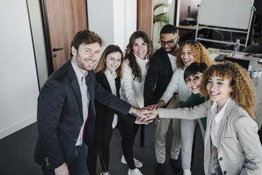 Glückliche Geschäftskollegen, die sich im Coworking-Büro die Hände reichen - EBBF05425