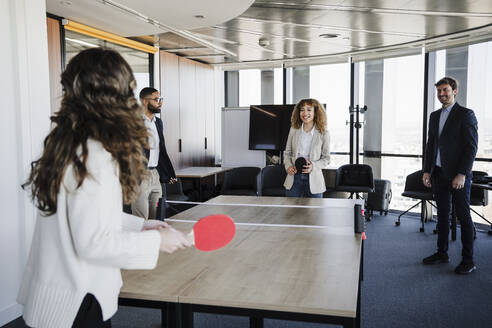 Geschäftsfrauen spielen Tischtennis und vergnügen sich mit Kollegen im Büro - EBBF05443