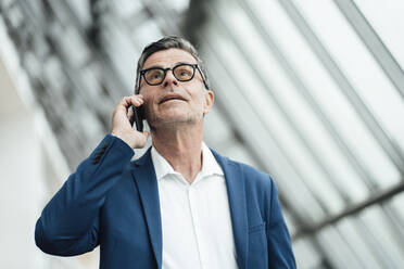 Businessman talking on smart phone at office - JOSEF06931