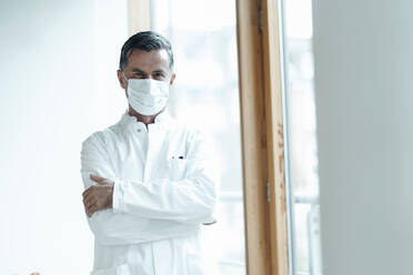 Scientist with protective face mask standing at medical clinic - JOSEF07022