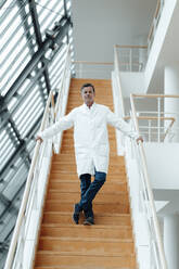 Wissenschaftlerin steht auf einer Treppe und hält sich am Geländer einer Klinik fest - JOSEF07037