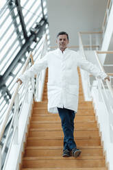 Wissenschaftler, der sich an einem Geländer festhält, steht auf einer Treppe in einer Klinik - JOSEF07038