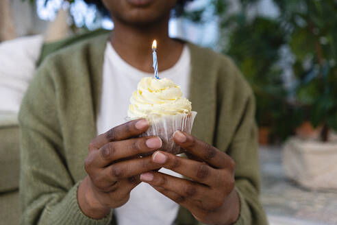 Junge Frau mit Kerze auf Muffin zum Geburtstag - VPIF05317