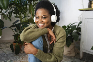 Smiling woman listening music on headphones at home - VPIF05329