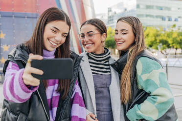 Lächelnde junge Frauen nehmen Selfie auf Smartphone in der Stadt - JRVF02679