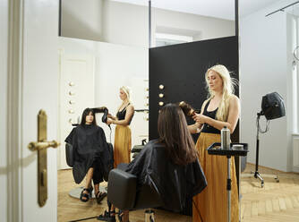 Friseurin stylt das Haar eines Kunden im Salon - CVF01892