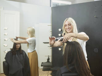 Happy hairstylist cutting customer's hair in salon - CVF01895