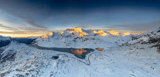 Kurvenreiche Straße des Berninapasses in der Winterlandschaft nahe des zugefrorenen Lago Bianco bei Sonnenaufgang, Engadin, Graubünden, Schweiz, Europa - RHPLF21261