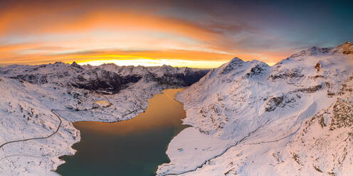 Luftaufnahme des Lago Bianco und der Berninapassstrasse über die schneebedeckten Berge in der Morgendämmerung, Engadin, Graubünden, Schweiz, Europa - RHPLF21262