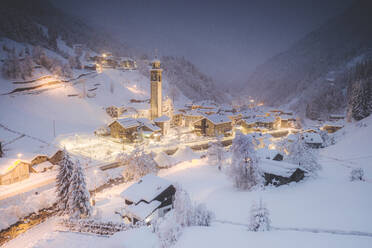 Illuminated village of Gerola Alta and frozen river covered with snow during winter dusk, Valgerola, Valtellina, Lombardy, Italy, Europe - RHPLF21266