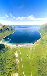 Luftaufnahme einer Straße in grünen Wiesen, die zum malerischen, vom kristallklaren Meer umspülten Strand des Ersfjords führt, Senja, Troms, Norwegen, Skandinavien, Europa - RHPLF21284