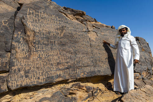 Mann zeigt auf Felszeichnungen, Bir Hima Rock Petroglyphs and Inscriptions, UNESCO-Weltkulturerbe, Najran, Königreich Saudi-Arabien, Naher Osten - RHPLF21335