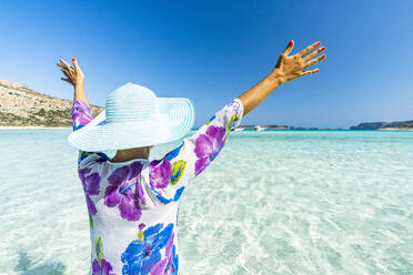 Fröhliche Frau mit erhobenen Armen beim Sonnenbaden im klaren Meer, Kreta, Griechische Inseln, Griechenland, Europa - RHPLF21409