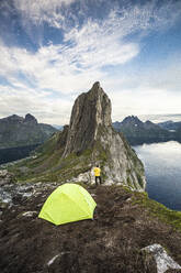 Wanderer mit Zelt und Blick auf den Berg Segla und den Fjord vom Gipfel des Hesten bei Sonnenuntergang, Senja, Provinz Troms, Norwegen, Skandinavien, Europa - RHPLF21411