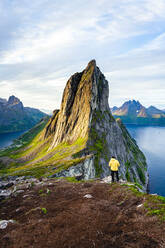 Person standing in front of tall Segla Mountain and fjords at dawn, Senja island, Troms county, Norway, Scandinavia, Europe - RHPLF21412