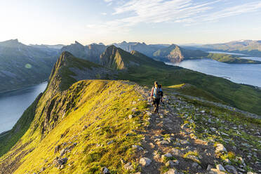 Rückansicht eines Mannes auf dem Weg zum Gipfel des Husfjellet bei Sonnenaufgang, Insel Senja, Provinz Troms, Norwegen, Skandinavien, Europa - RHPLF21420