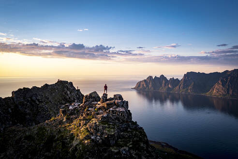 Person, die den Sonnenuntergang vom Gipfel eines Berges betrachtet, Insel Senja, Provinz Troms, Norwegen, Skandinavien, Europa - RHPLF21423