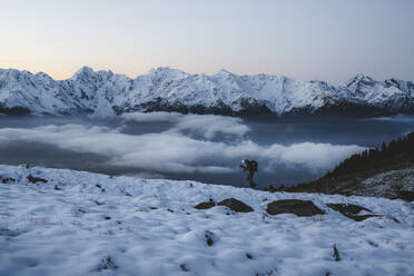 Mann mit Wanderstöcken beim Wandern im Schnee mit den majestätischen Orobie-Alpen im Hintergrund, Alpe Rogneda, Rhätische Alpen, Lombardei, Italien, Europa - RHPLF21431