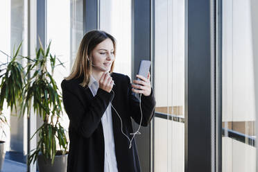 Arbeitende Frau, die an einem Videogespräch über ein Smartphone im Büro teilnimmt - EBBF05468