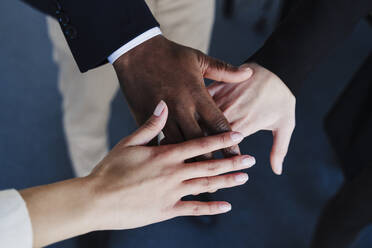 Multi-ethnic business colleagues stacking hands - EBBF05469