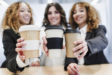 Geschäftskollegen mit Einweg-Kaffeebechern im Coworking-Büro - EBBF05498