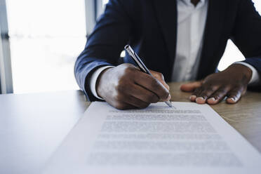 Client signing contract at table in office - EBBF05517