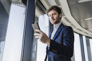 Businessman using smart phone in office - EBBF05565