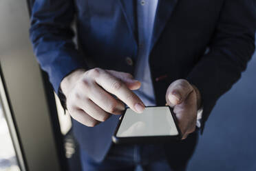 Hands of businessman touching screen of smart phone in office - EBBF05567