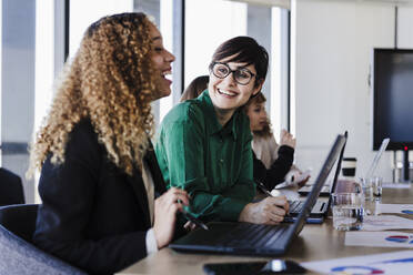 Glückliche Geschäftskollegen am Schreibtisch im Coworking-Büro - EBBF05587