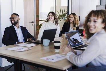 Multi-ethnic business colleagues attending meeting sitting at desk in coworking office - EBBF05593