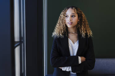 Contemplative businesswoman with arms crossed in office - EBBF05597