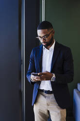 Geschäftsmann mit Brille benutzt Smartphone im Büro - EBBF05599