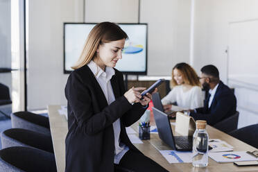 Geschäftsfrau benutzt Smartphone im Sitzungssaal eines Coworking-Büros - EBBF05607