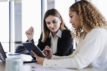 Geschäftsfrauen arbeiten gemeinsam an einem Tablet-PC in einem Coworking-Büro - EBBF05609