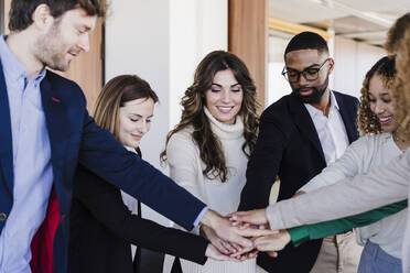 Multi-ethnic business colleagues stacking hands in coworking office - EBBF05617