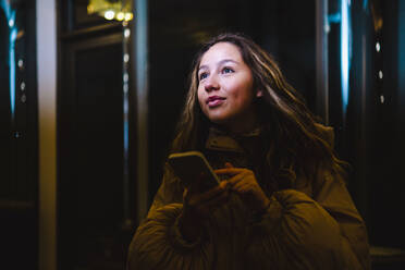 Contemplative woman with smart phone at night - AMWF00168