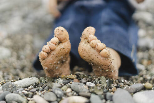 Schmutzige Beine eines Jungen auf Kieselsteinen am Strand - SEAF00470