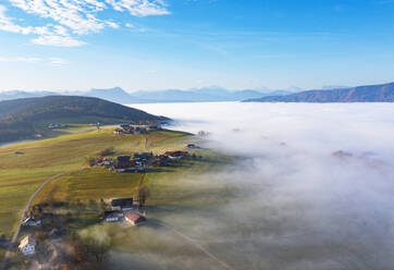 Drohnenansicht eines Bergdorfs und eines in dichten Morgennebel gehüllten Tals - WWF06090