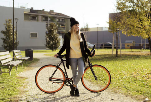 Nachdenkliche Frau mit Fahrrad im Park - GIOF14851