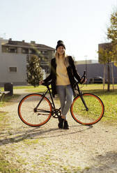 Happy woman with bicycle in park - GIOF14852