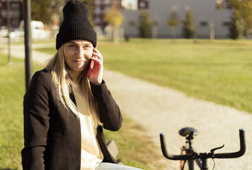 Young woman talking on smart phone in park - GIOF14853